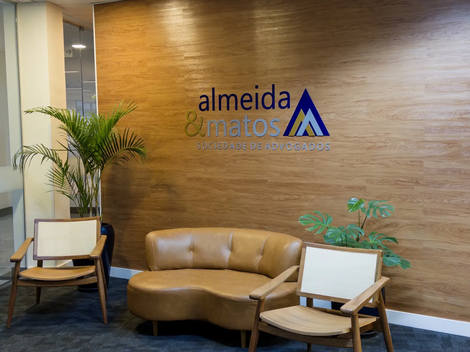 Recepção da Almeida & Matos em Alphaville, Barueri (SP), com o logo do escritório na parede